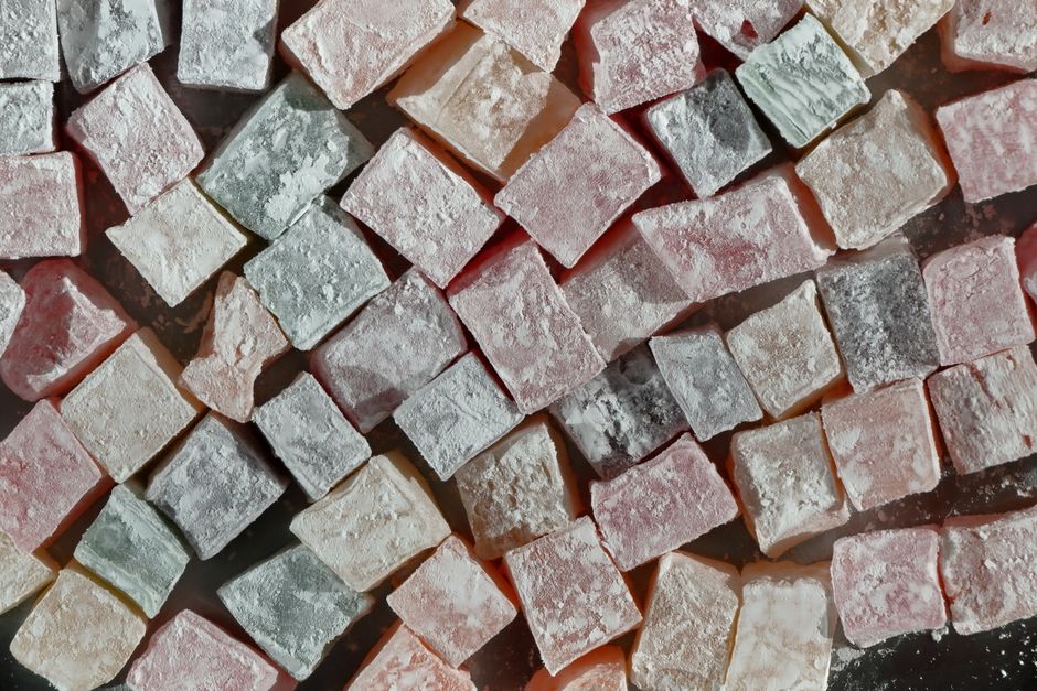 Close-up of assorted colorful Turkish delight cubes with powdered sugar coating.