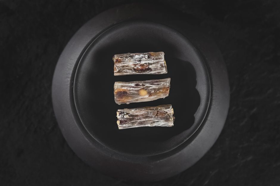 Three pieces of Turkish delight elegantly arranged on a black plate, captured in a minimalist style.