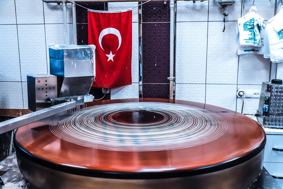 Large machinery in a Turkish kitchen with a flag in the background, showcasing food production.
